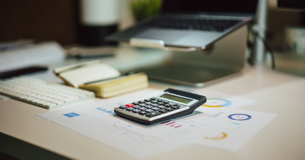 Calculator, laptop și documente folosite pentru estimarea unui buget