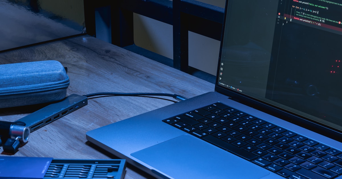 Laptop deschis cu un editor de cod pe un birou